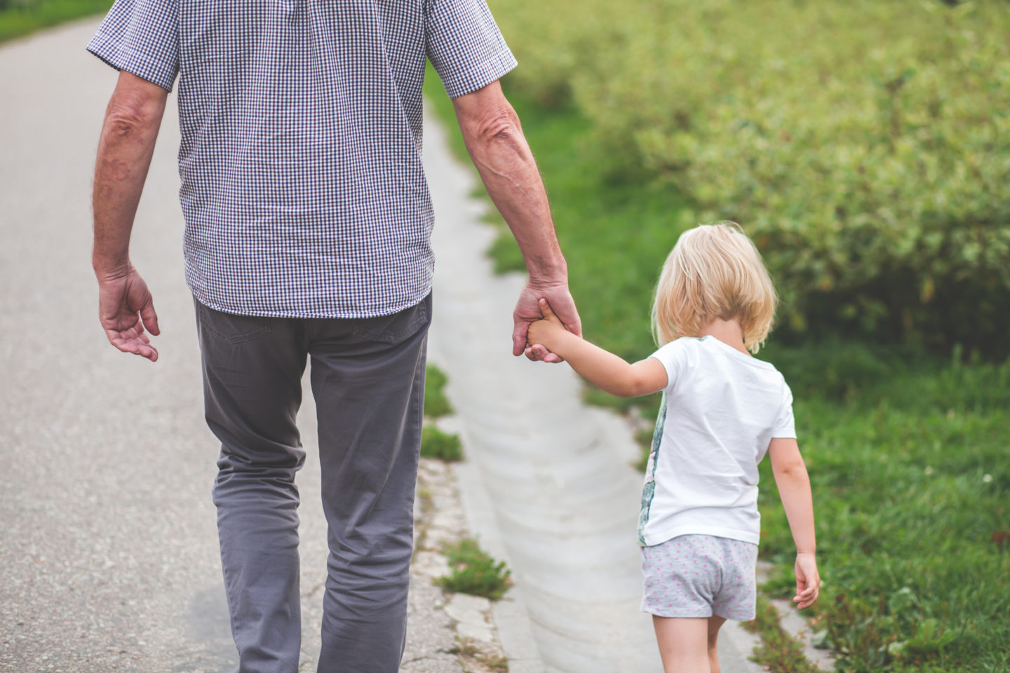 multi-generational travel - a grandfather holding hands with his granddaughter